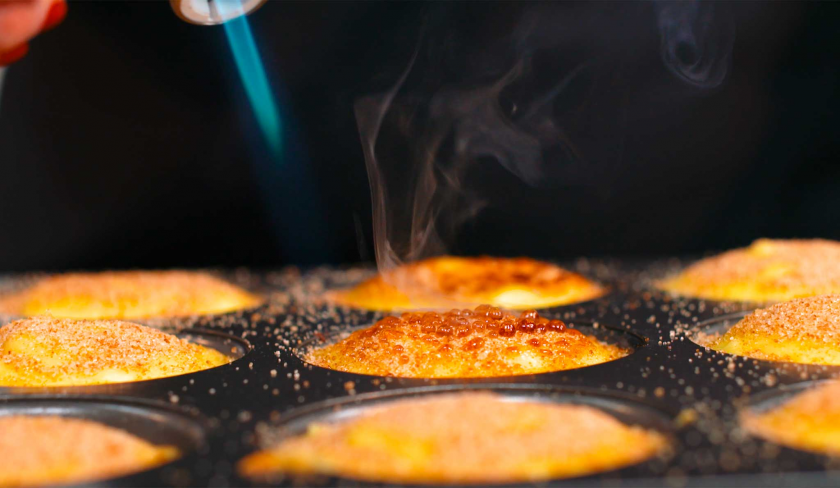 Der Zucker auf den Crème Brulée Brownie Törtchen wird mit einem Bunsenbrenner karamellisiert.