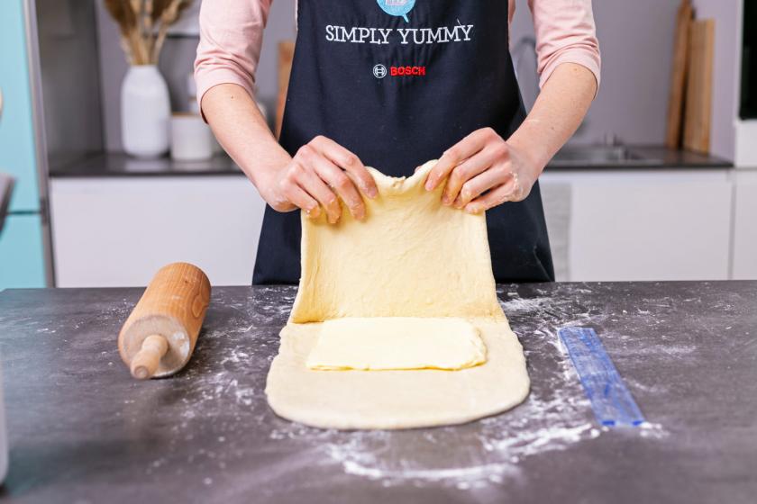 Croissant Teig wird um Butterplatte geschlagen.