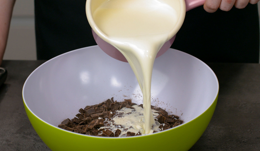 Für die Ganache für den Death by Chocolate wird Sahne auf gehackte Schokolade in einer Schüssel gegossen.
