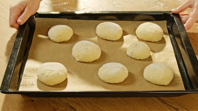 Rohe Dinkel Burger Buns liegen auf einem Backblech.