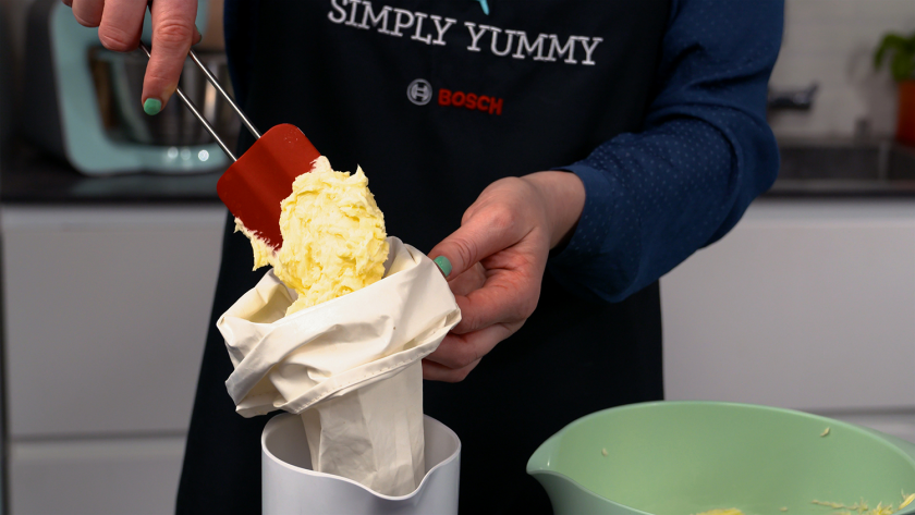 Buttercreme für die Verzierung des Donauwellen-Gugelhupfs wird in eine Spritztülle gefüllt.