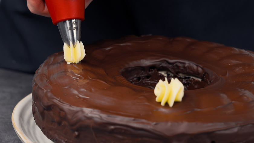 Der Donauwellen-Gugelhupf wird mit Buttercremetupfen verziert.