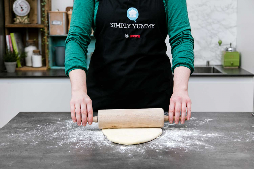 Der Teig für die Donuts wird ausgerollt.