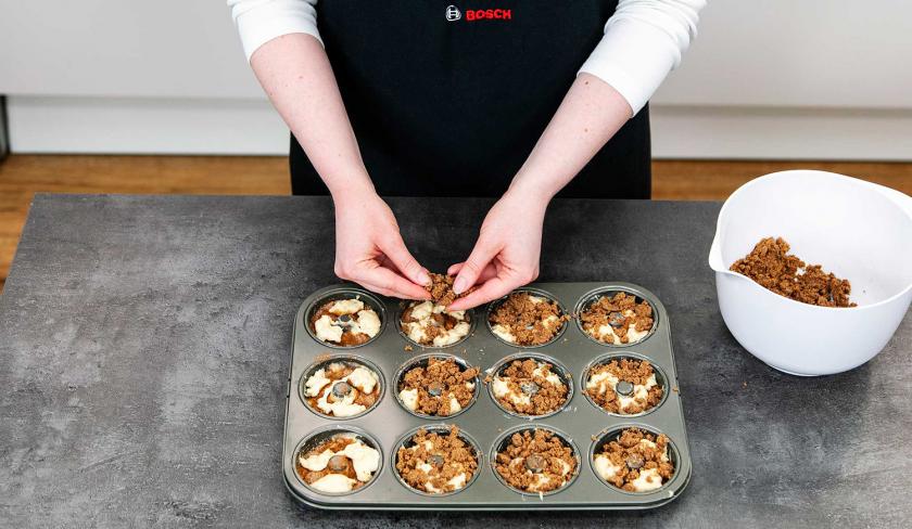 Die Donuts werden mit Zimtstreuseln bedeckt.