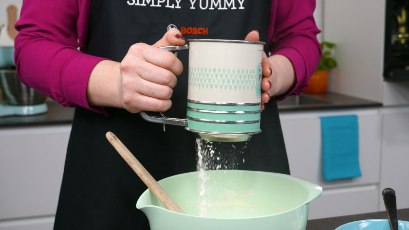 Die trockenen Zutaten für den Eierlikör Drip Cake mit weißer Schokolade werden in die Teigmasse gesiebt.
