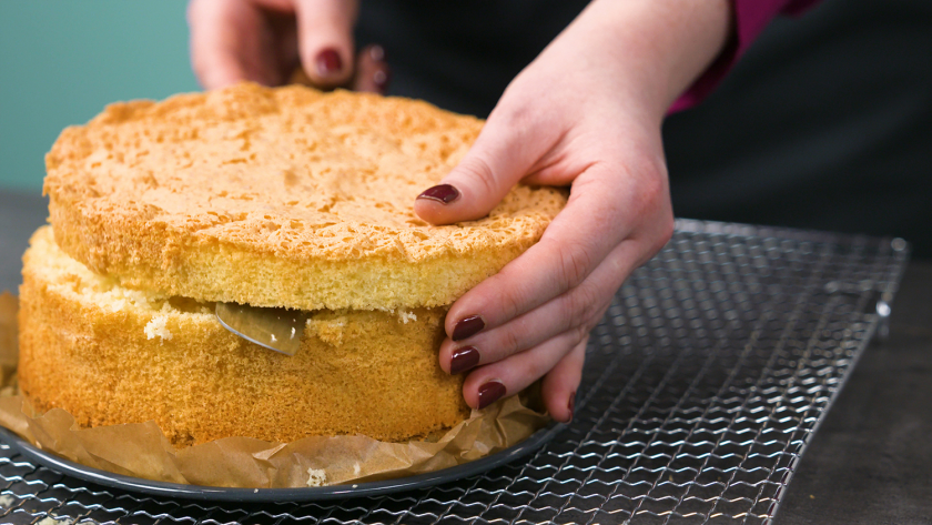 Der Biskuitboden für den Eierlikör Drip Cake mit weißer Schokolade wird waagerecht durchgeschnitten.