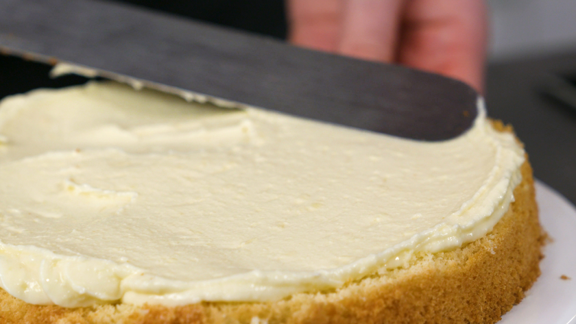Der Boden des Eierlikör Drip Cake mit weißer Schokolade wird mit Creme bestrichen.