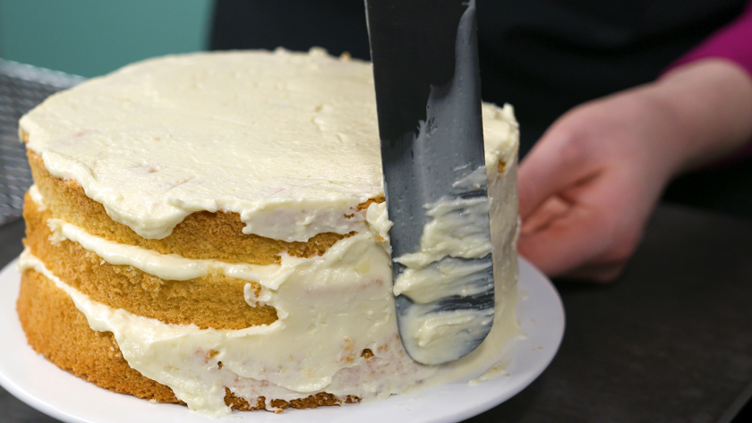 Der Biskuit für den Eierlikör Drip Cake mit weißer Schokolade wird rundherum mit Creme eingestrichen.