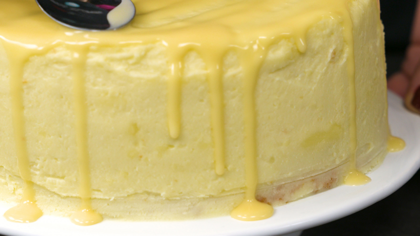 Der Eierlikör auf dem Eierlikör Drip Cake mit weißer Schokolade wird mit einem Löffel verteilt.