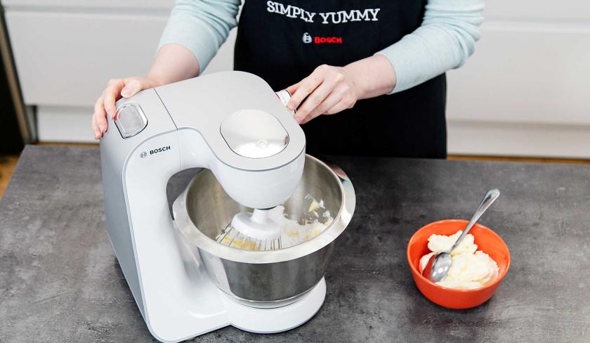 In einer Küchenmaschine wird Frischkäse cremig gerührt.