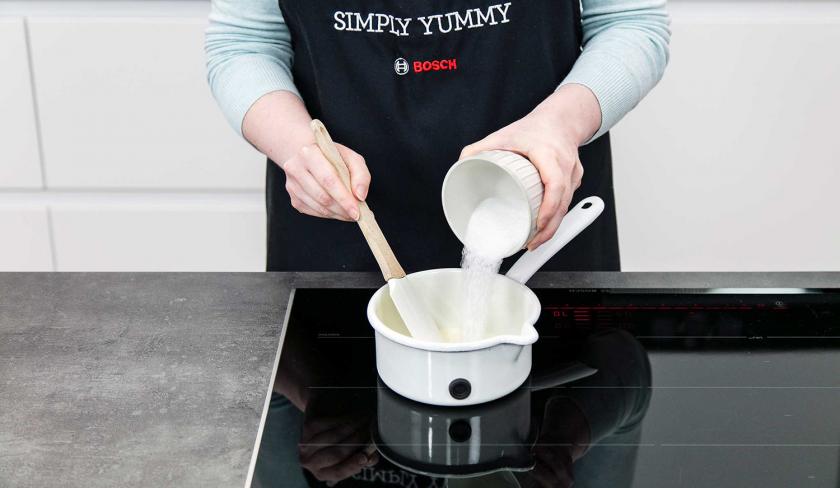 Für die Kaffeecreme der Eiskaffee-Torte wird Zucker zu Sahne in einen Topf gegeben.