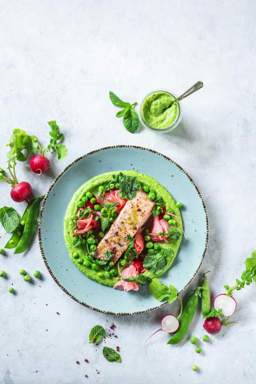 Erbsen-Minz-Püree mit Radieschen und Lachs auf einem Teller angerichtet.