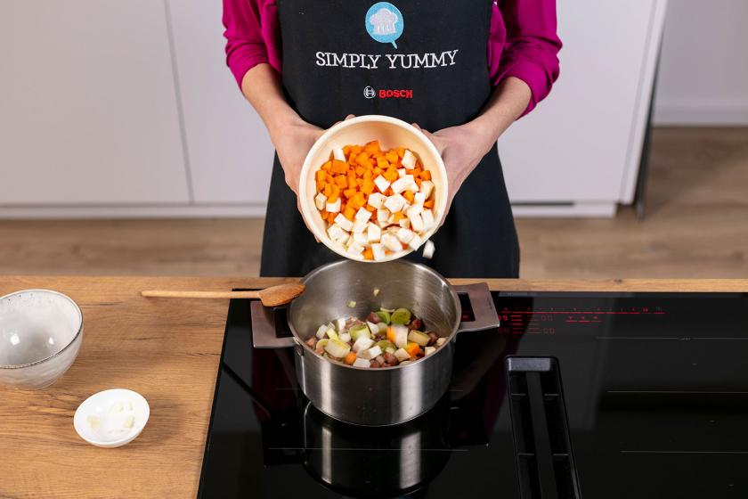 Gewürfeltes Gemüse wird in einen Topf gegeben.