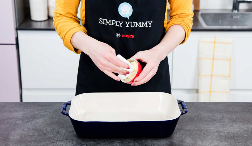 Eine Auflaufform wird für den Erdbeer-Rhabarber-Cobbler eingefettet.