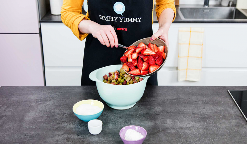 Erdbeeren für die Füllung des Erdbeer-Rhabarber-Cobblers werden zu Rhabarber in eine Schüssel gefüllt.