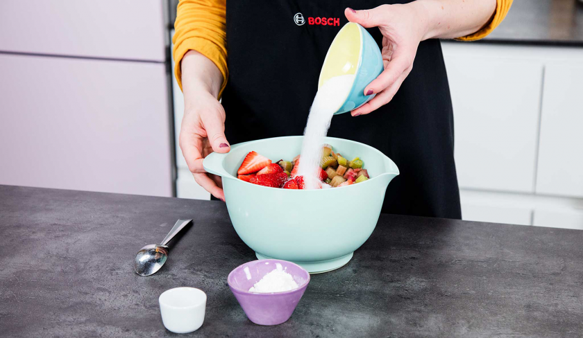 Zur Füllung des Erdbeer-Rhabarber-Cobblers wird Zucker gegeben.