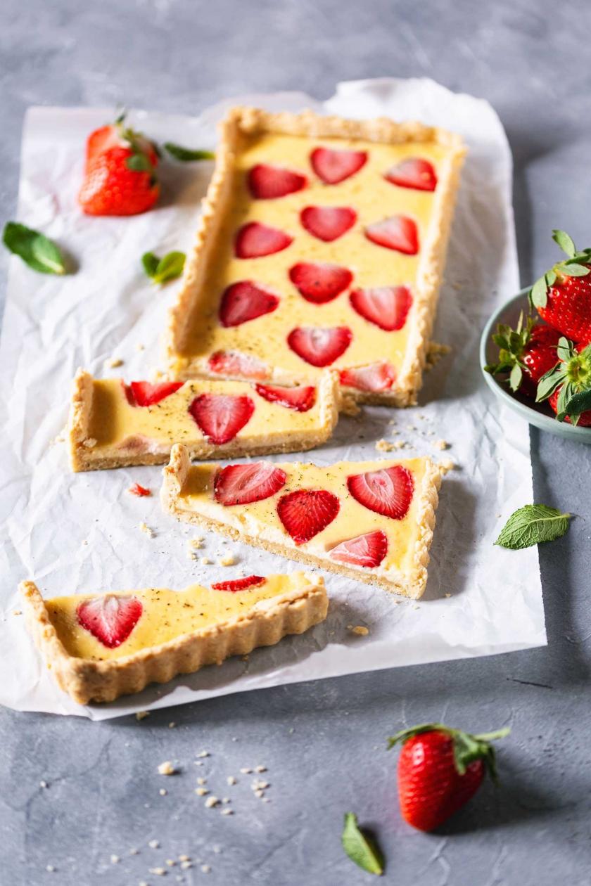 Erdbeer-Schmand-Tarte in Stücken auf einem Stück Backpapier.