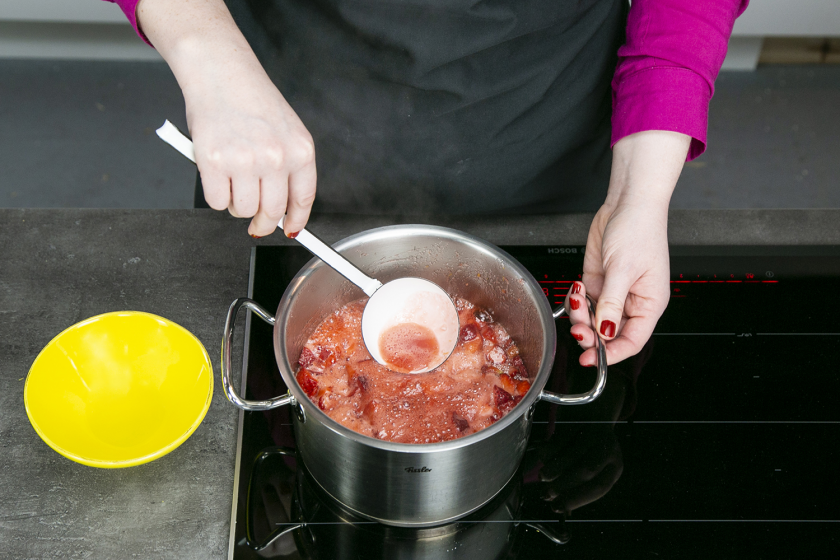 Beim Kochen der Erdbeermarmelade wird der Schaum mit einer Kelle abgeschöpft.