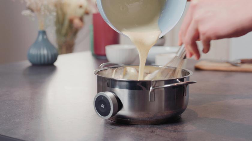 Eigelb-Stärke-Mischung wird in die heiße Milch eingerührt.