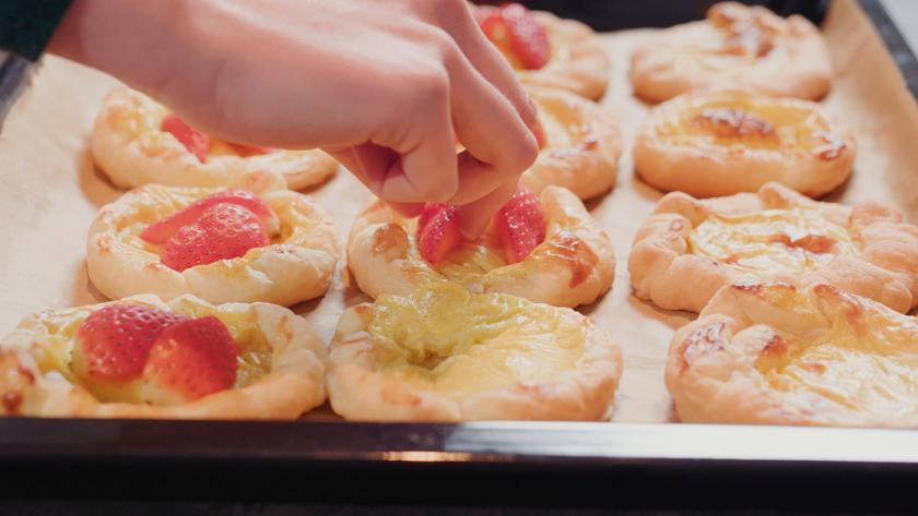 Die Erdbeerplunder werden mit Erdbeerhälften belegt.