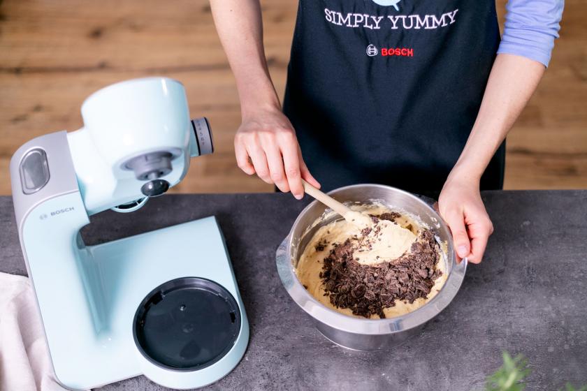 Schokolade wird unter den Teig für den Erdnusskuchen gehoben.