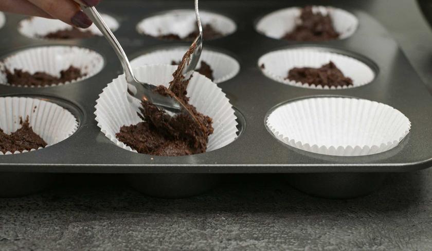 Der Teig für die Espresso-Muffins mit weißer Schokolade wird in die Förmchen gefüllt.