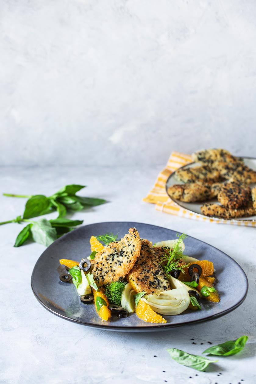 Fenchel aus dem Ofen mit panierten Schnitzelchen auf einem Teller mit Salat angerichtet.