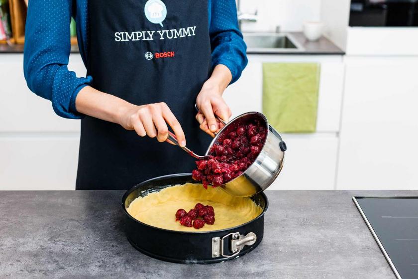 Kirschkompott wird auf den Mürbeteigboden des Feuerwehrkuchens verteilt.