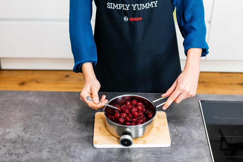 Kirschen werden in einem Topf vermengt.