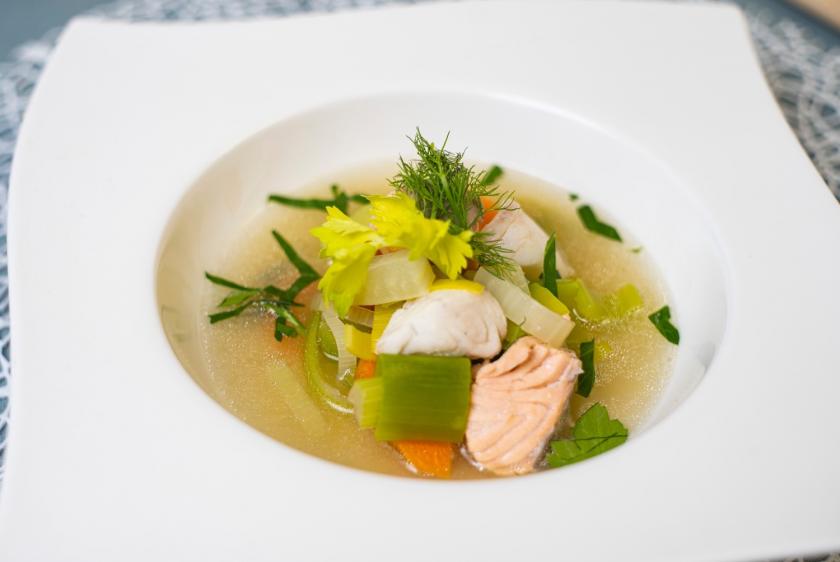 Fischsuppe mit Gemüse in weißem tiefen Teller.