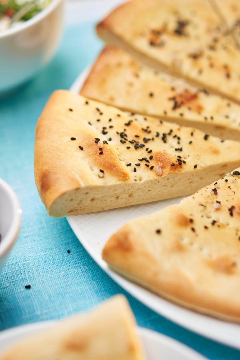 Fladenbrot türkischer Art mit Schwarzkümmel und Pfeffer in Stücke geschnitten auf einem Teller.