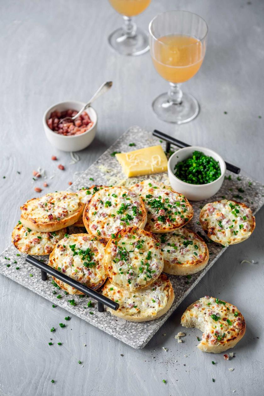 Mehrere Flammkuchen Brötchen auf einem Brett mit Schnittlauch.