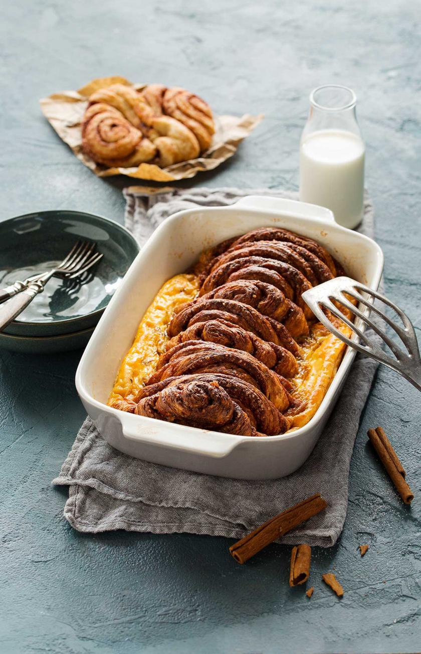 Franzbrötchen-Auflauf auf einem Tisch mit Geschirr und Milch.