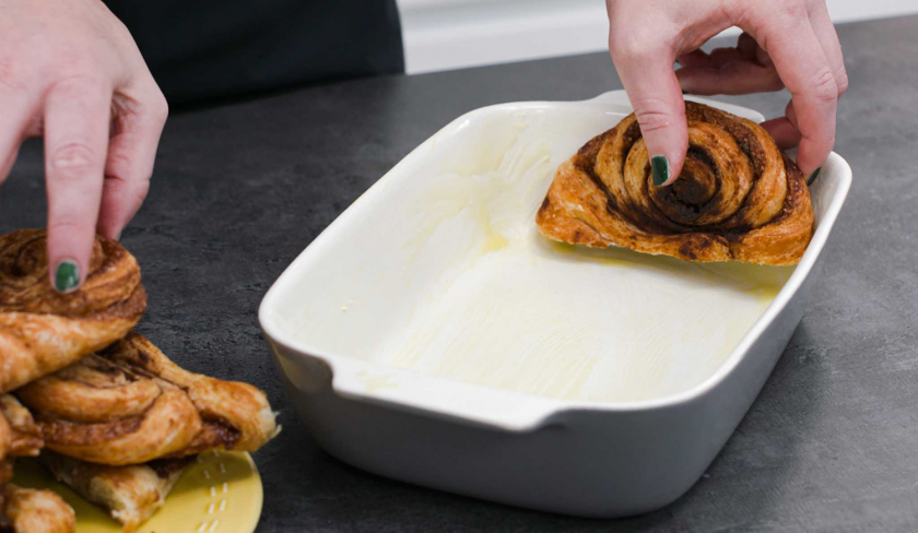 Für den Franzbrötchen-Auflauf wird das halbierte Gebäck in eine Auflaufform geschichtet.