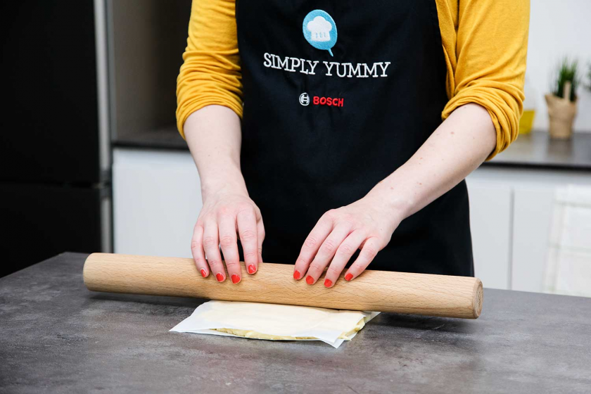 Für den Plunderteig der Franzbrötchen wird Butter zwischen Backpapierlagen ausgerollt.