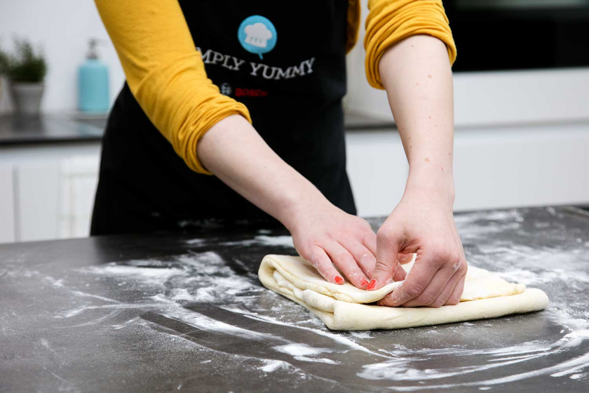 Der Teig der Franzbrötchen wird übereinander gefaltet.