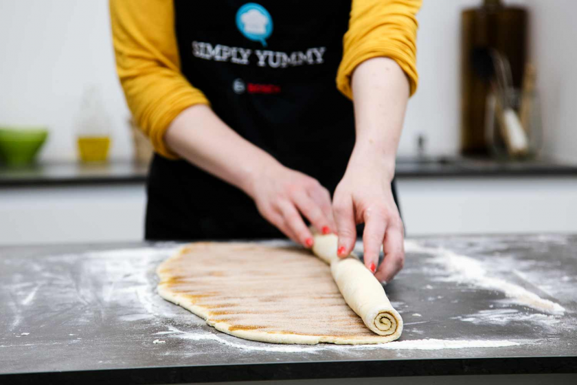 Der Teig der Franzbrötchen wird aufgerollt.