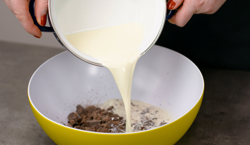 Für die Füllung des fruchtiger Mosaik Kuchens wird Sahne zu Schokolade in eine Schale gegeben.