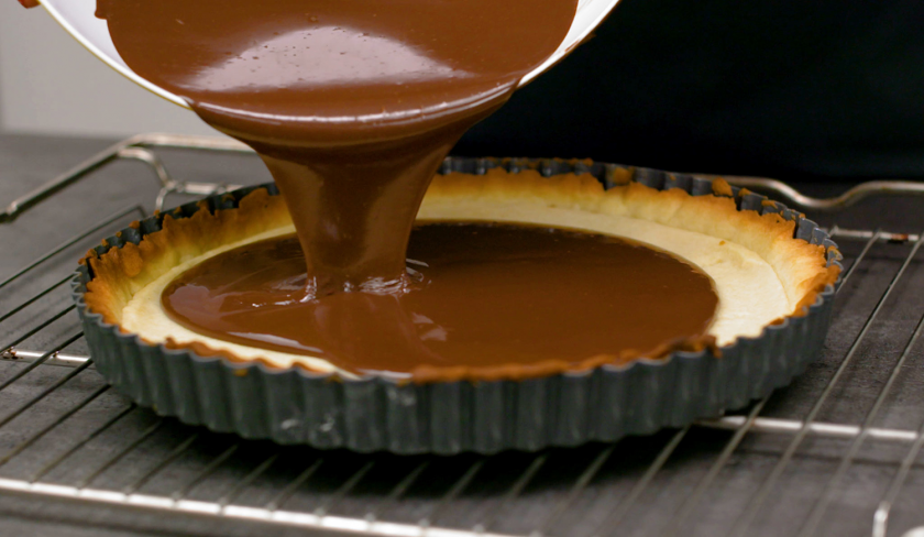 Die Ganache für fruchtiger Mosaik Kuchen wird auf den Boden gegossen.