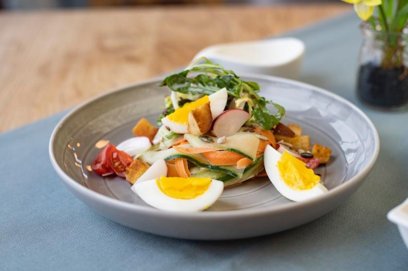 Frühlingssalat mit Ei und Croûtons auf grauem Teller