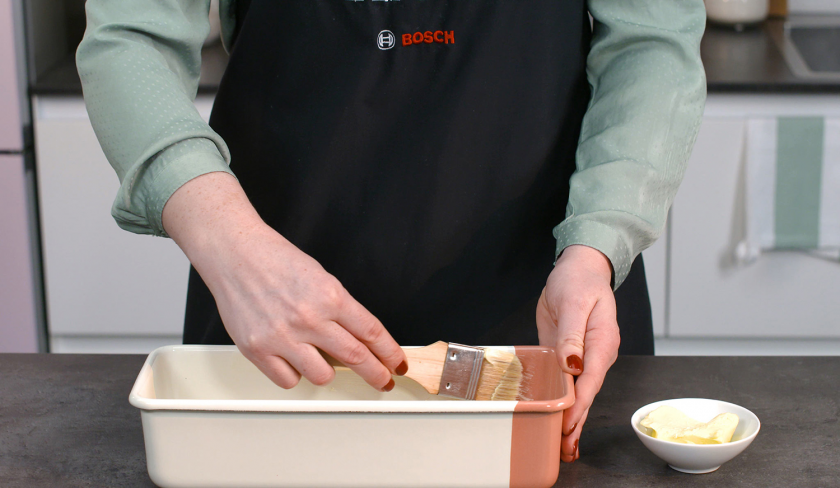 Für den gefüllter Schoko-Erdbeerkuchen wird eine Kastenform eingefettet.