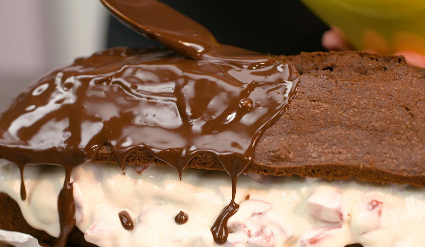 Gefüllter Schoko-Erdbeerkuchen wird mit Ganache eingestrichen.