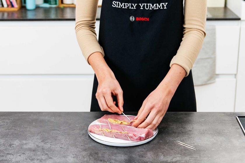 Gefülltes Schweinefilet wird mit Zahnstochern verschlossen.