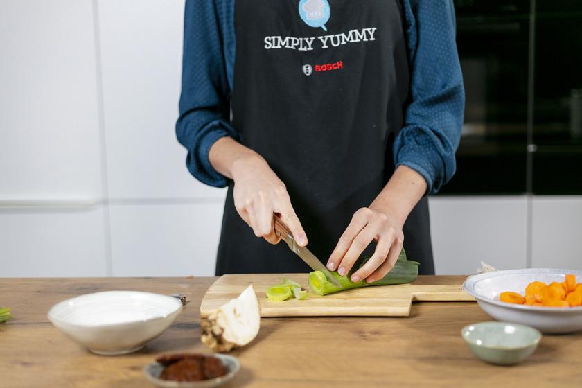 Lauch wird auf einem Holzbrett in Ringe geschnitten.