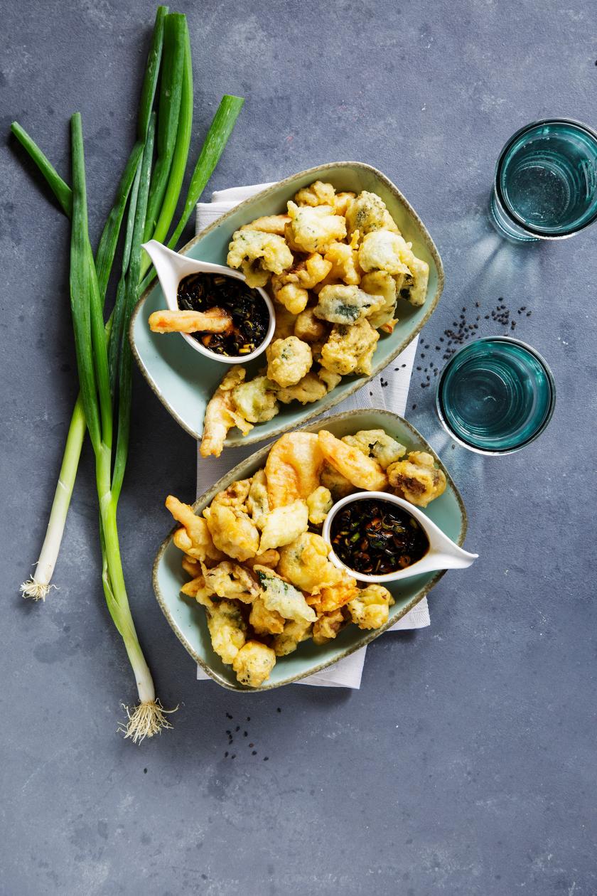Gemüse-Tempura mit Sojasoße auf zwei Tellern angerichtet.