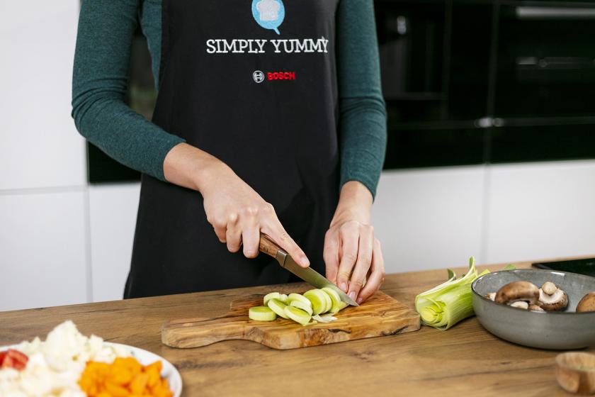 Lauch wird auf einem Holzbrett in Ringe geschnitten.