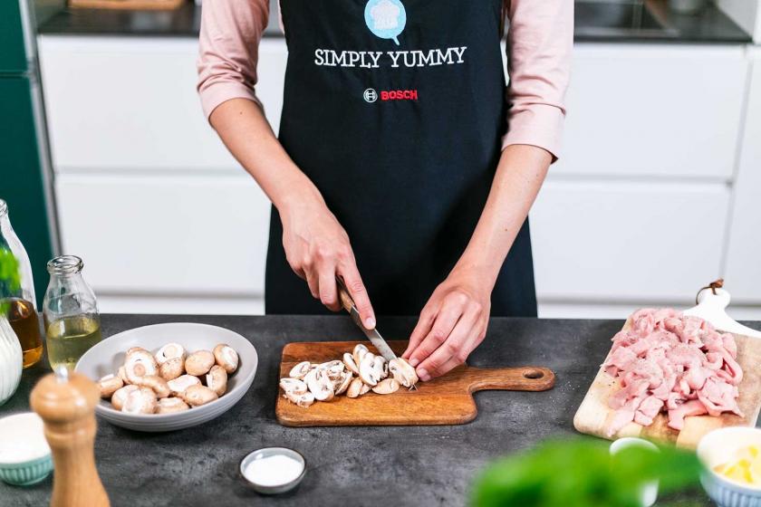 Champignons werden auf einem Brett in Scheiben geschnitten.