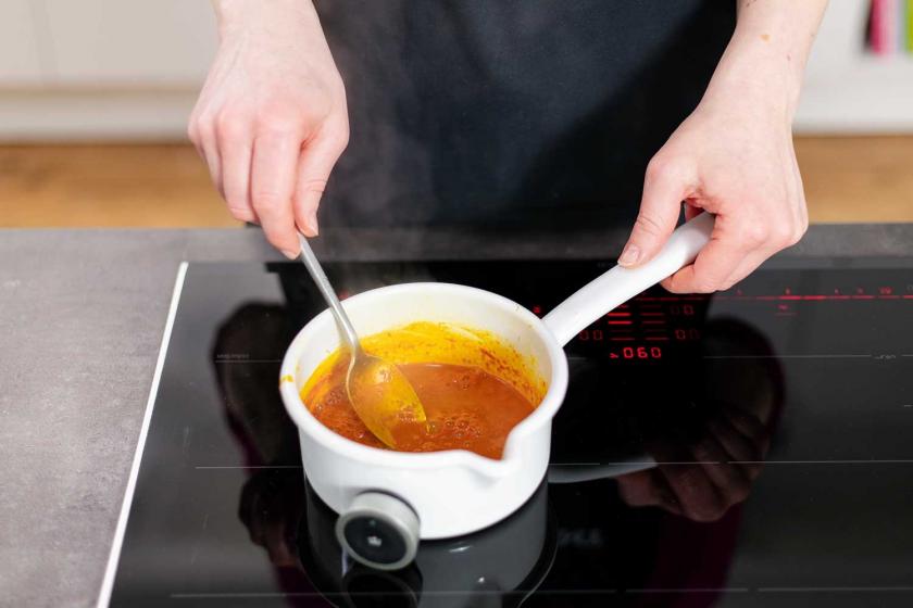 Die Kurkuma-Ingwer-Paste für die Goldene Milch wird in einem Topf gekocht.