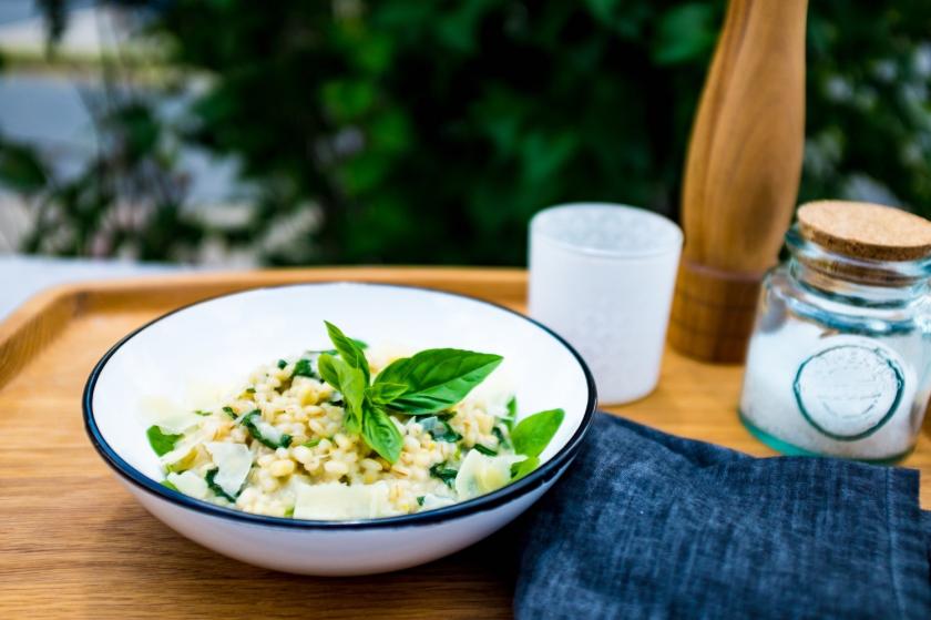 Graupenrisotto mit Spinat in einer Emaille-Schüssel auf Gartentisch