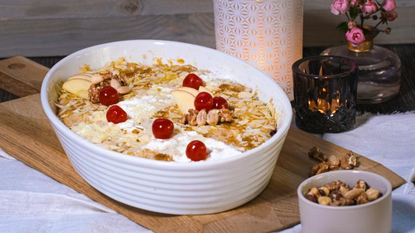 Grießauflauf in weißer Auflaufform mit Mandelkruste und Kirschen garniert.